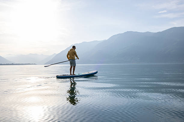 istock Man Paddleboarding on Serene Lake at Sunrise 2213678605