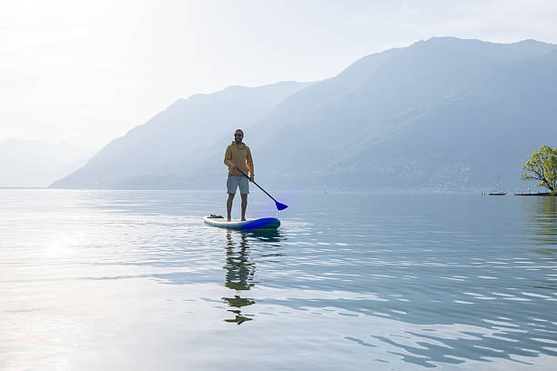 istock Man Paddleboarding on Calm Mountain Lake at Sunset 2213678741