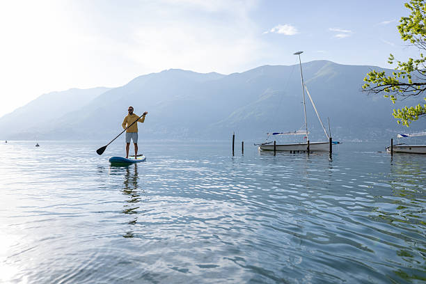 istock Man Paddleboarding on Tranquil Lake at Sunrise 2213678888
