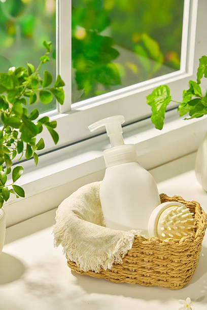 istock Unlabeled shampoo bottle placed in a wicker basket with a white hand-held comb, lined with a beige burlap cloth. The basket sits on a windowsill surrounded by potted plants. Spa accessories 2213679435