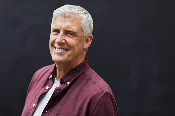 istock Smiling mature man standing against wall 2213679822