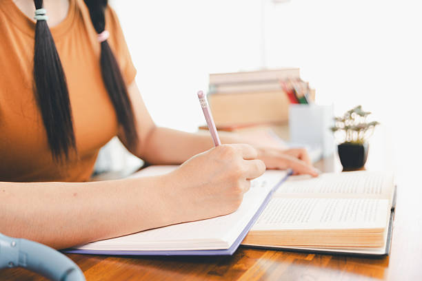 istock woman sitting at desk working on laptop taking notes in notebook, female studying online, watching webinar using computer, writing check list. Remote college school education, e learning concept. 2213682723