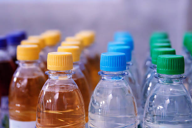 istock Plastic water and beverage  bottles with multicolored caps arranged in rows for packaging and consumer product display. Selective focus 2213684499
