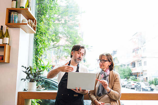 istock Cafe owner consults with financial adviser using laptop in a bright cafe setting. They collaborate on strategy, showcasing small business growth, digital planning, and entrepreneurial teamwork. 2213687117