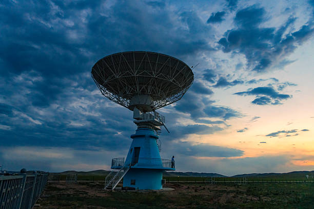 An engineer is repairing a satellite receiver under the sunset.