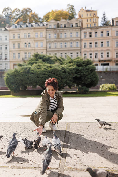 istock Woman feeding pigeons on old spa town square 2213688577