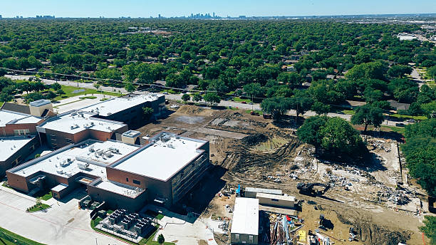 istock Elementary school remodel construction site preparation, paving, utilities storm drainage near lush green residential area Northaven Road with downtown Dallas skyline background, bitumen roof 2213689078