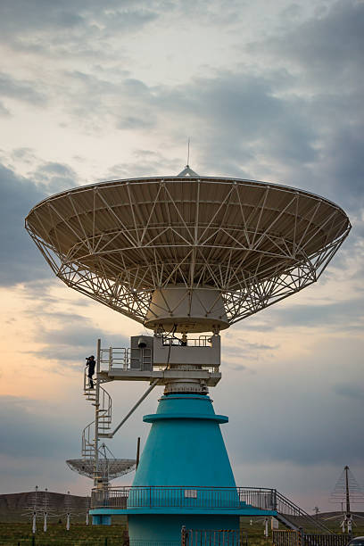 An engineer is repairing a satellite receiver under the sunset.