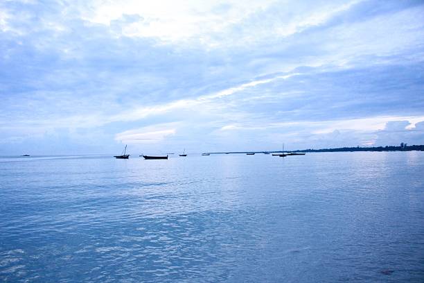 A serene seascape with boats on a calm ocean under a cloudy sky, capturing tranquility and natural beauty.