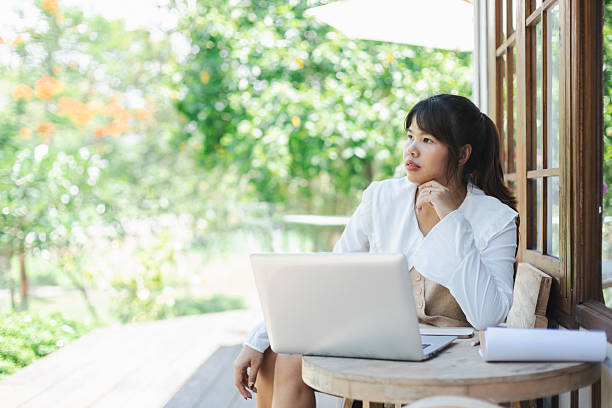 istock Asian woman working remotely as digital nomad looks thoughtfully outside while using laptop in peaceful outdoor workspace 2213712844