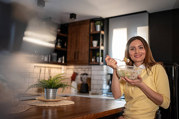 istock Young woman eating a salad in her modern kitchen 2213714048