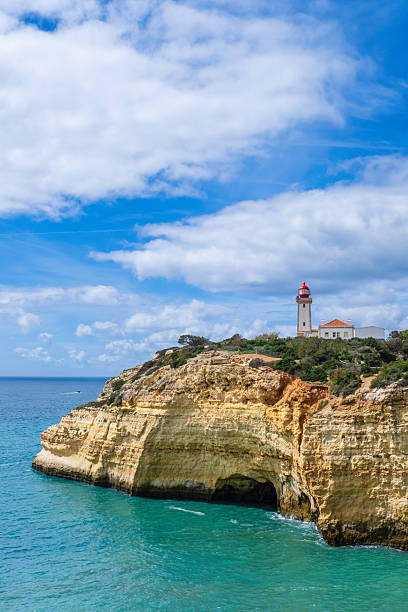 The quadrangular tower, painted in white, of the Alfanzina lighthouse stands out on a rocky promontory in the Algarve