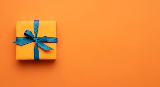 istock Orange color gift wrap decorated with blue ribbon top vie on empty space background.Discount,halloween. 2213722019