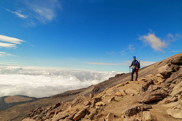 Kilimanjaro, Tanzania - March 9, 2015: Kibo with Uhuru Peak (5895m amsl) at Mount Kilimanjaro, Kilimanjaro National Park, seen from Karanga Camp at 3995m amsl. Park sign and tents in the background.