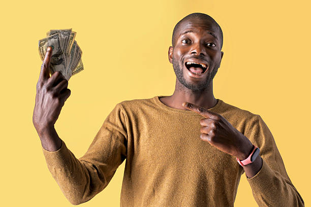 istock Smiling man holding cash and pointing finger with cheerful expression 2213728249