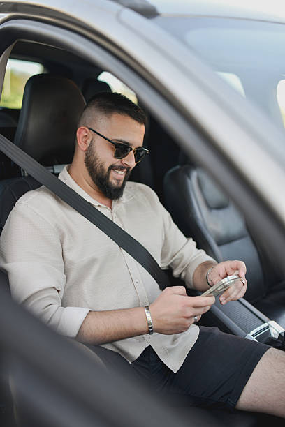 istock Joyful Male Smiling When Receiving Funny Message on Phone While Sitting in Car 2213728267