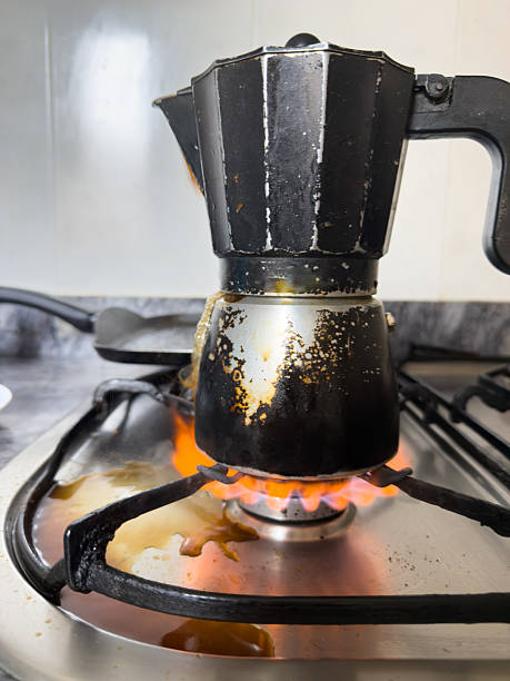 istock Dirty coffee pot overflowing on gas stove making a mess in kitchen 2213734923