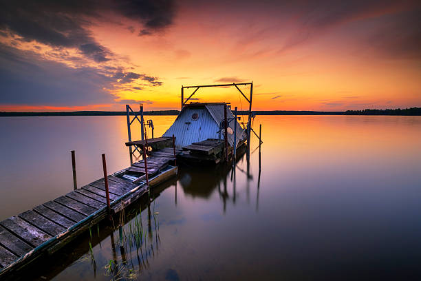Long exposure shot early in the morning at sunrise on calm lake, sunlight reflecting in water, swimming pier