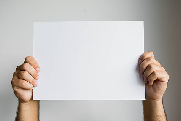 istock Hands holding blank white paper against neutral background 2213735728