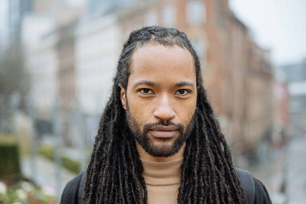 istock Black tourist with dreadlocks visiting city on rainy day, looking at camera 2213735856