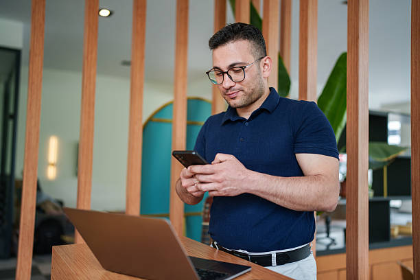 istock Male Office Worker Checking Smartphone at Standing Desk 2213736176