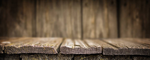 Vintage wooden tabletop with aged planks in sharp focus and a blurred wooden wall background. Ideal for product display, food mockups, or rustic-themed design projects.
