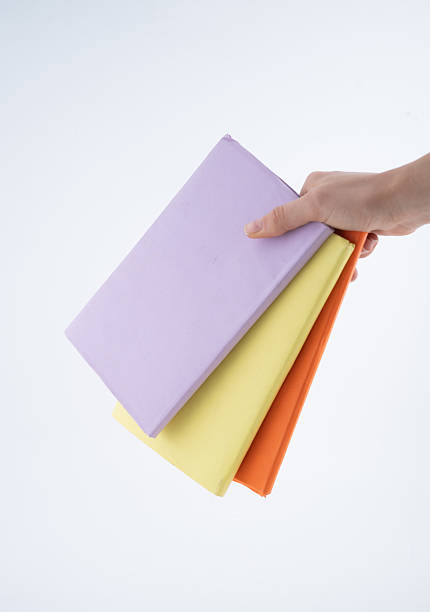 istock Hand Holding Three Colorful Books in a Simple Setting 2213737139
