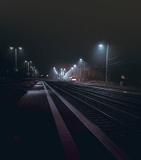 istock Moody nighttime train station with illuminated platforms. 2213738303