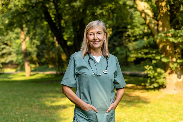 istock Mature caucasian female nurse looking positive while standing on a greenery background 2213741143