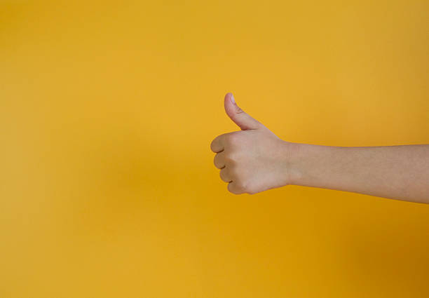 istock Hand young boy thumb up isolated on yellow color background. 2213742621