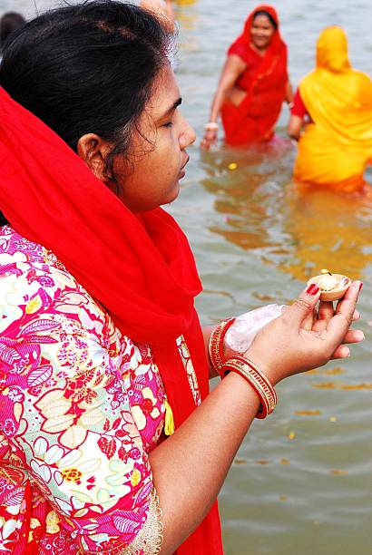 Pilgrim woman standing on the water of the Maa Ganga river while she holds a \