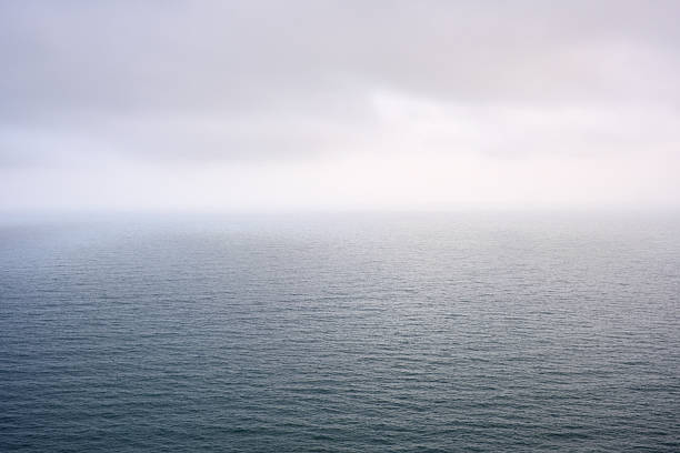 Calm ocean landscape under cloudy sky: minimalist seascape with overcast atmosphere