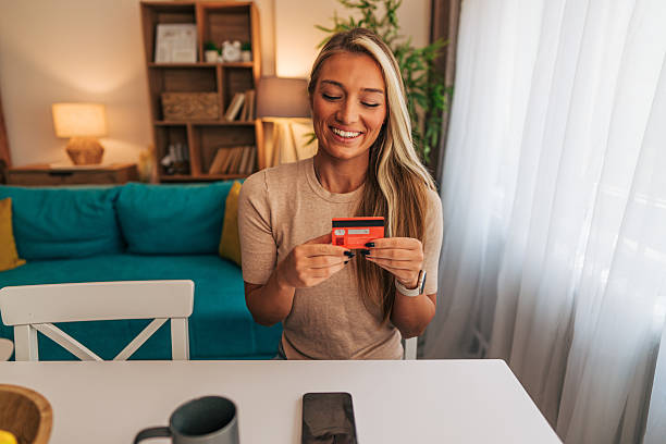 istock Smiling woman making online payment using credit card at home 2213747075