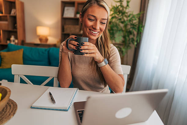 istock Young woman working remotely from home drinking coffee and smiling 2213747471