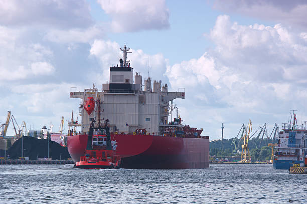istock Tugboat guiding a large cargo ship through a busy harbor under a bright sky 2213749038