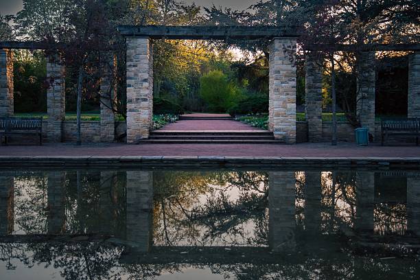 istock Tranquil garden with stone columns and pond reflection. 2213750896