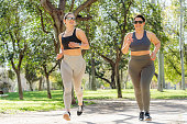 Overweight woman and slim woman jogging together in the park
