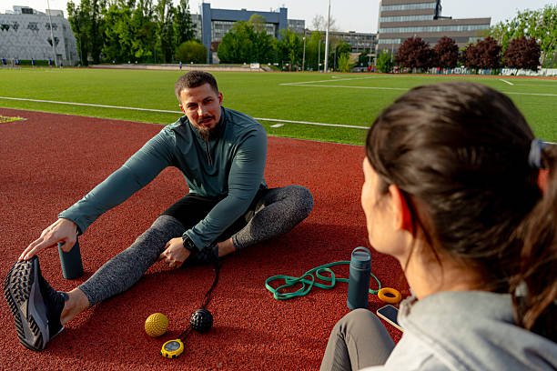 istock Athletes stretching together on a running track after training 2213758012