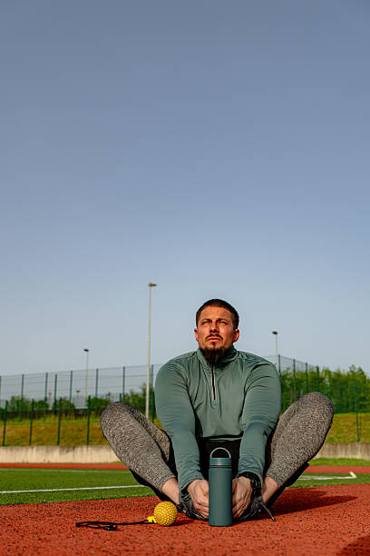 Athlete stretching legs on running track in butterfly position