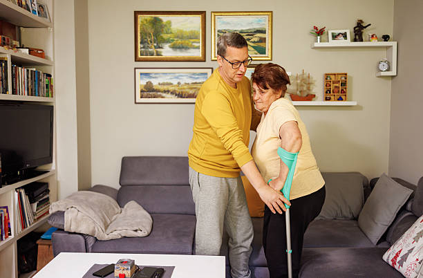 istock An Elderly Woman Leaning Forward, Her Crutch and Son By Her Side Lifting her 2213761611