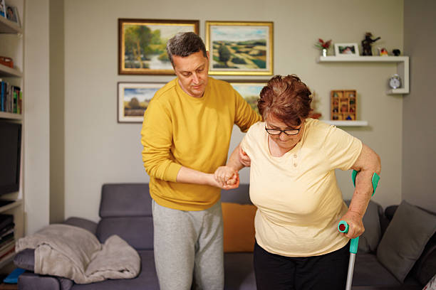 istock Son giving his elderly mother a hand while she trying to stand with a crutch 2213761878