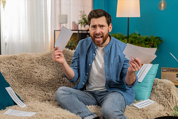 istock Man throwing home utility bills on sofa, desperate about financial debt, frustration 2213762735