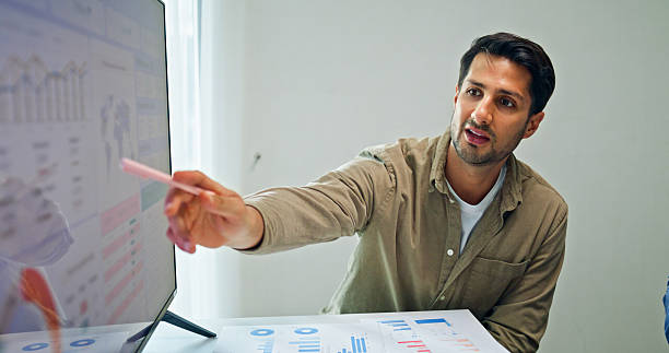 istock Group of business professionals meeting reviewing global data analytics presented on a large screen, discussing strategy and growth at the office. Finance meeting concept. 2213765681