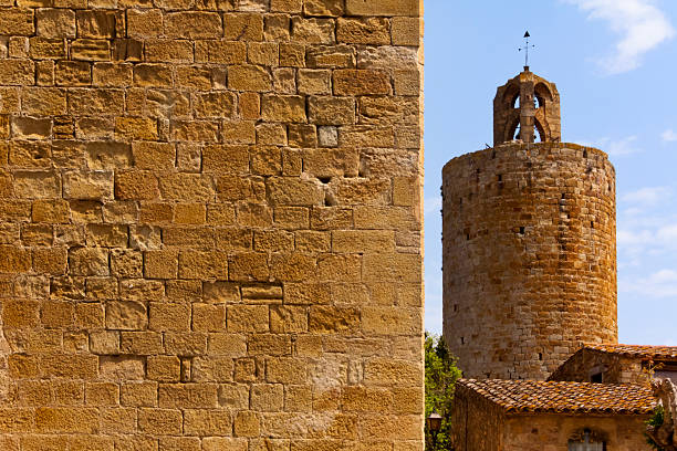 Hours tower, street view  in Pals, Girona, Catalunya, Spain. Townscape. Weathered stone wall in the foreground.
