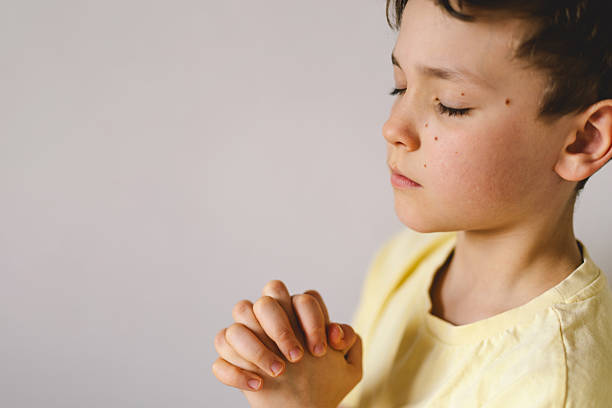 istock A boy with folded hands in front of him, he is praying or meditating 2213766844