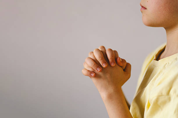 istock A boy with folded hands in front of him, he is praying or meditating 2213766853