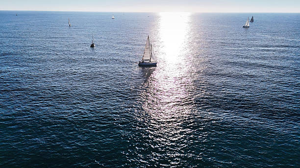 istock Sailboats sailing on blue ocean with sun reflection on water 2213769553