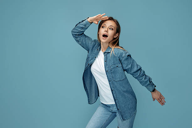 Excited woman in jeans shirt wearing headphones looking away with hand over eyes Excited woman in jeans shirt wearing headphones looking away with hand over eyes. hair covering eyes stock pictures, royalty-free photos & images