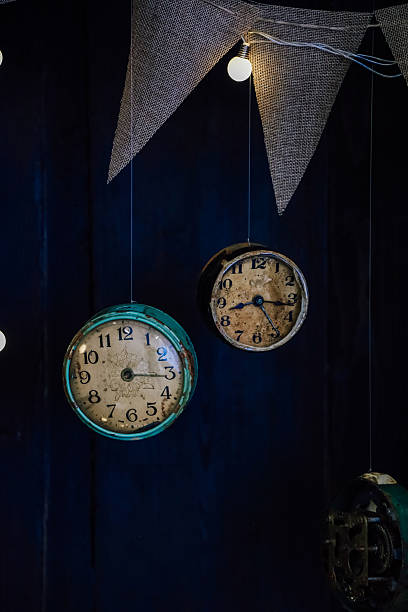 istock Vintage clocks hanging decoratively in a dimly lit space with warm lighting and fabric bunting 2213773646