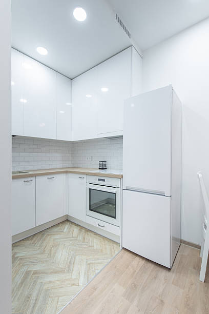 Stylish and minimalistic white kitchen interior showcasing modern cabinetry, sleek countertops, and built-in appliances in a bright and organized space
